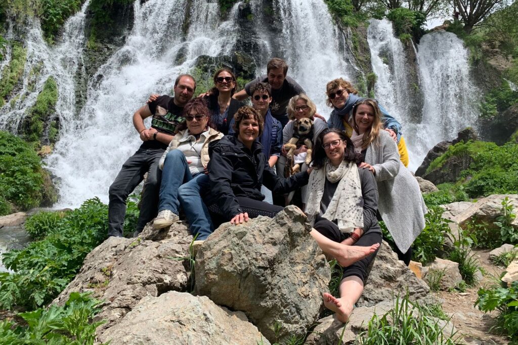 Michelle Natalya Moore and a group from the "Worry-free device-free experience" posing on rocks in front of a waterfall.
