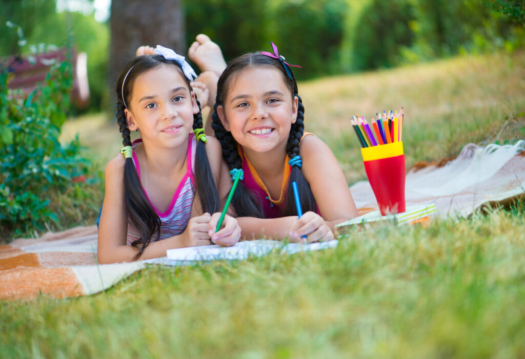 Hispanic sisters drawing in a summer park.