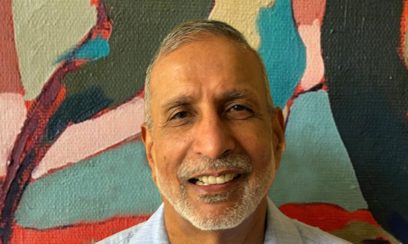 Headshot image of Headshot of Parmjit Singh Mangat in front of a painting.